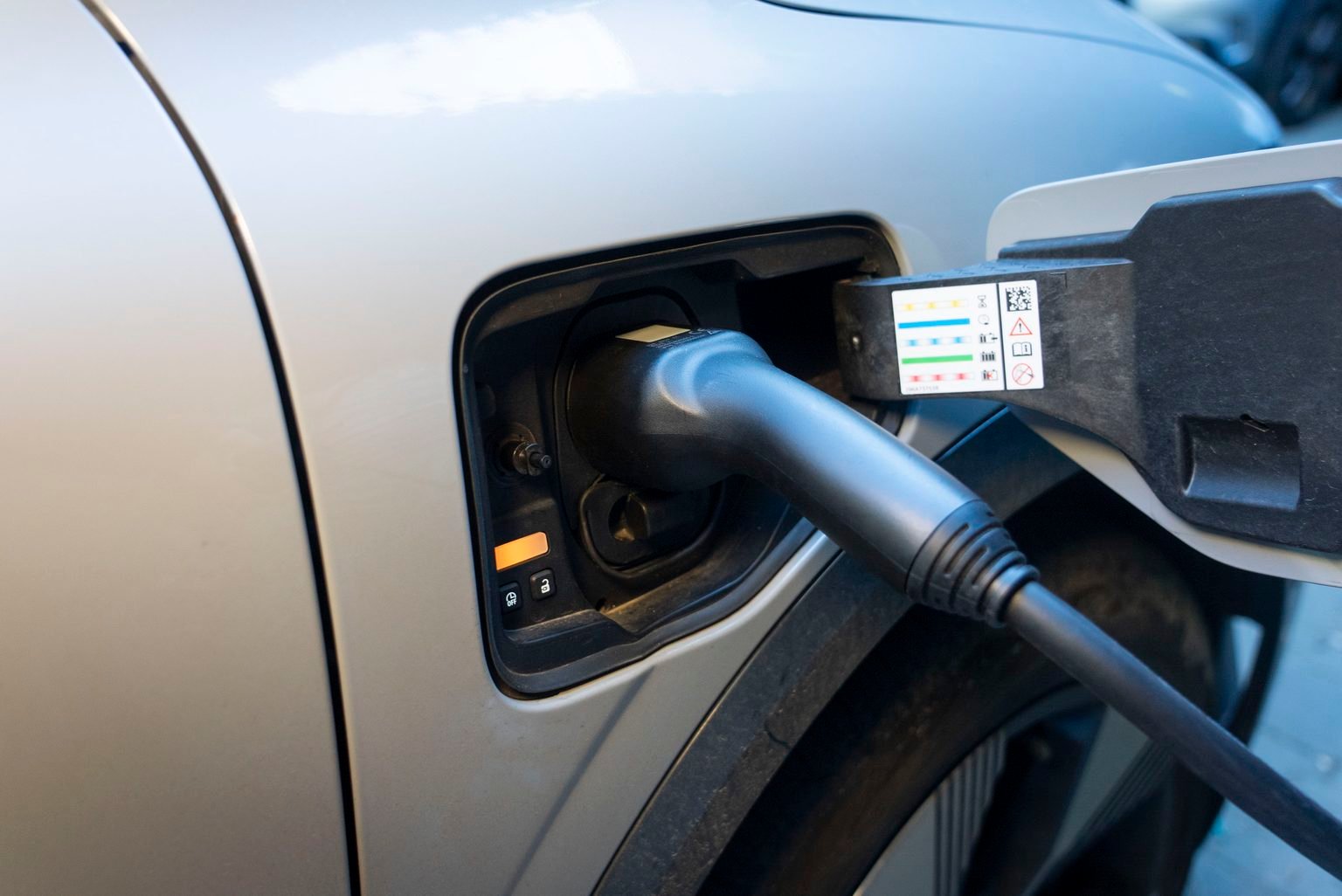 Conector de carga conectado al puerto de un auto eléctrico plateado
